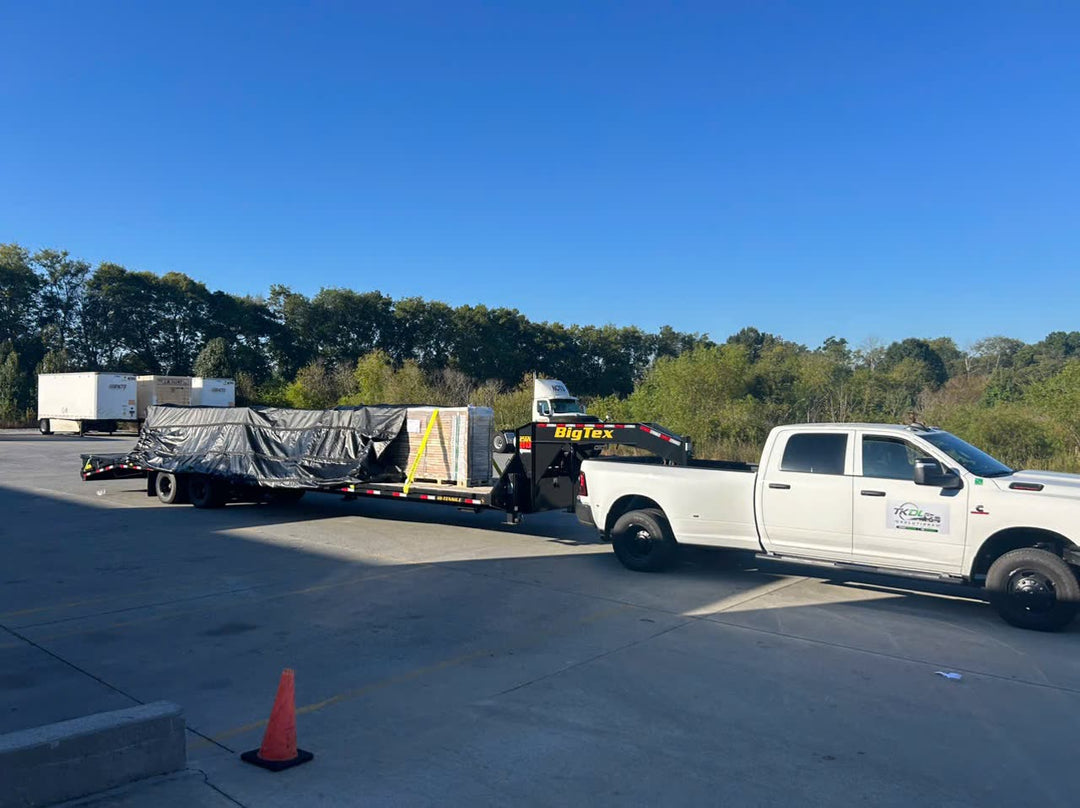 A pickup truck towing a tarped flatbed load of butcher block tops